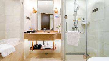 A modern bathroom with a bathtub, a sink with a mirror, a glass-enclosed shower, and a toilet.