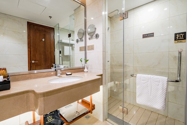 Un baño moderno con un espejo grande, un lavamanos y una ducha con cerramiento de vidrio.