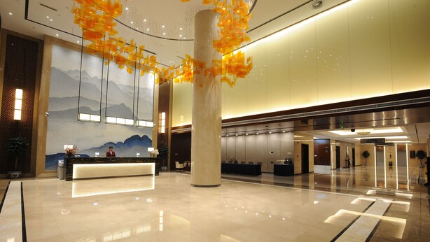 A spacious lobby with a reception desk, a large pillar, and a mural of mountains. - The Farrington Hotel - Building B (Weifang)