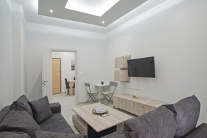 Een moderne woonkamer met een bank, een salontafel en een televisie aan de muur.