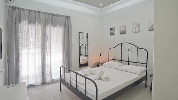 A bedroom with a skylight, a bed with white linens, a bedside table with a lamp, and artwork on the wall. - Sofia s Home in Piraeus (Piraeus)