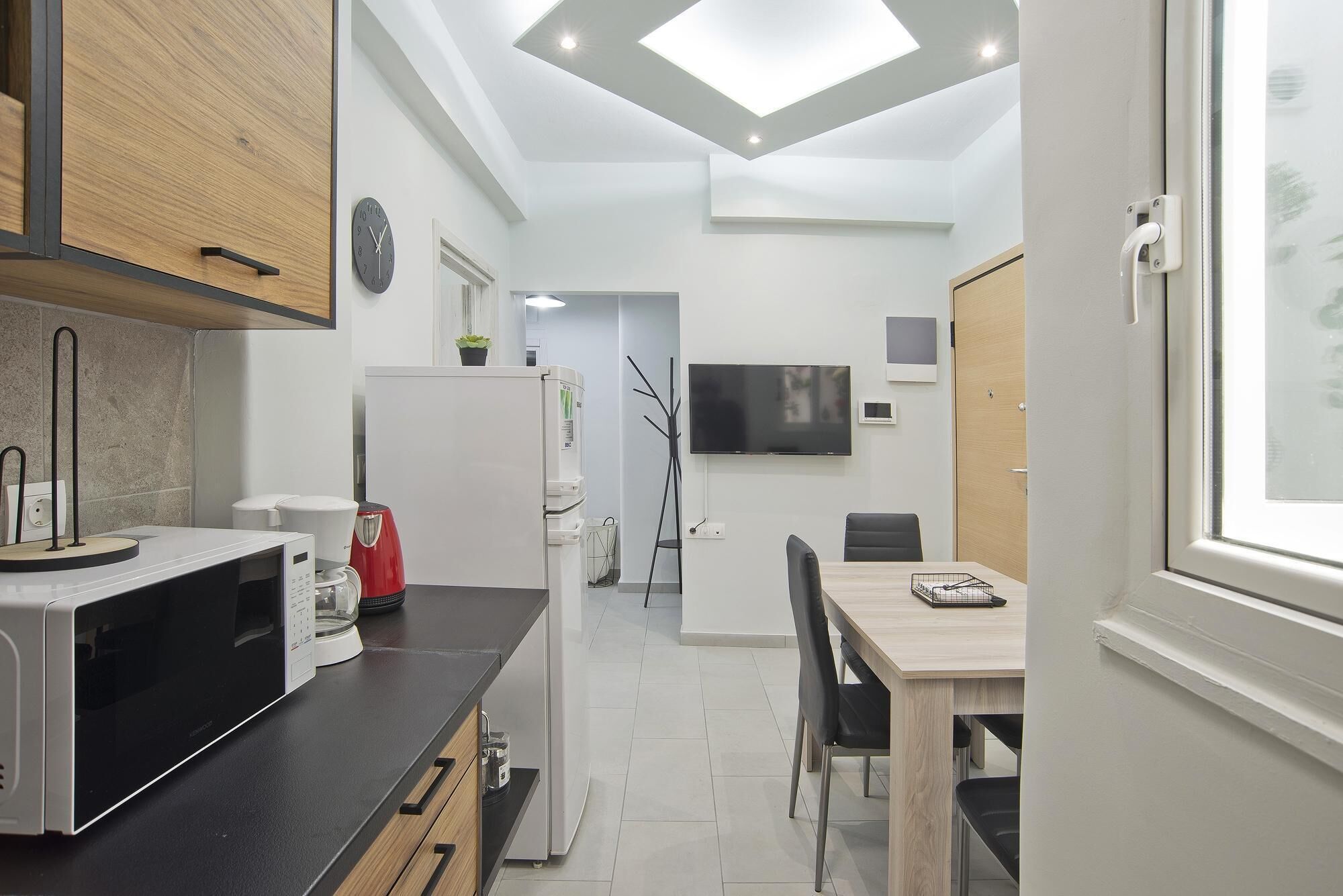 A modern kitchen with a microwave, refrigerator, and dining area with a table and chairs.