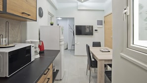 A modern kitchen with a microwave, refrigerator, and dining area with a table and chairs. - Sofia s Home in Piraeus (Piraeus)