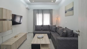 A modern living room with a flat-screen TV, grey sofa, wooden coffee table, and a skylight ceiling. - Sofia s Home in Piraeus (Piraeus)