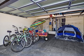 Eine Garage mit Fahrrädern, einem bunten Regenschirm, einem Wagen voller Gegenstände und einem Zelt.
