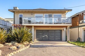 A two-story house with a garage, a balcony with glass railings, and a landscaped front yard with desert plants. - Oceanview Retreat with Hot Tub (Santa Cruz)