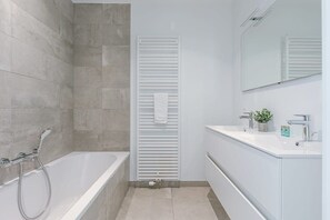Bathroom features a standalone bathtub, vanity with sink and mirror, and towel rack.