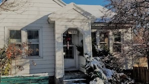 Une maison blanche avec un porche à l’avant et des marches menant à la porte, portant le numéro 2235.
