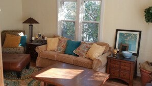Ein gemütliches Wohnzimmer mit Sofa, Couchtisch, Lampe, Beistelltisch mit Schale und einem gerahmten Bild an der Wand.