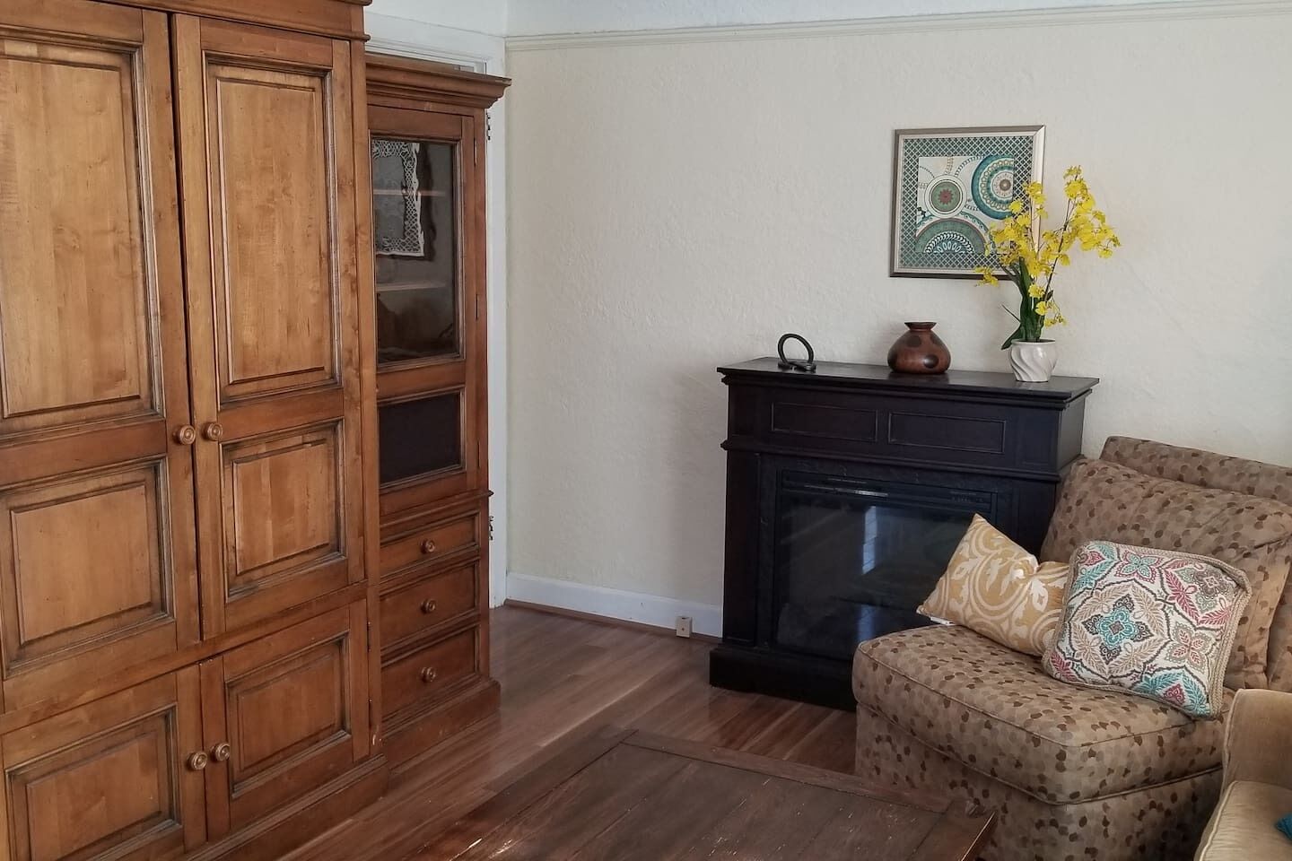 Una sala de estar con un aparador de madera, una chimenea y un sillón estampado.