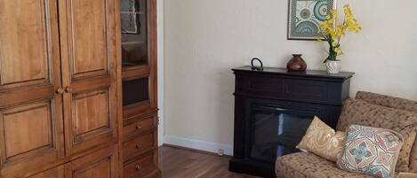 Una sala de estar con un aparador de madera, una chimenea y un sillón estampado.