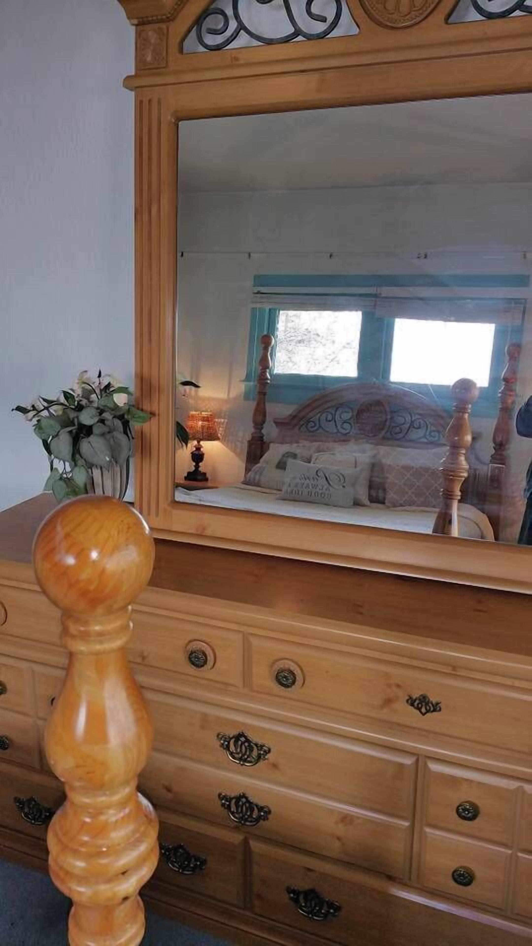 Un aparador de madera con espejo, cajones y un tirador decorativo.