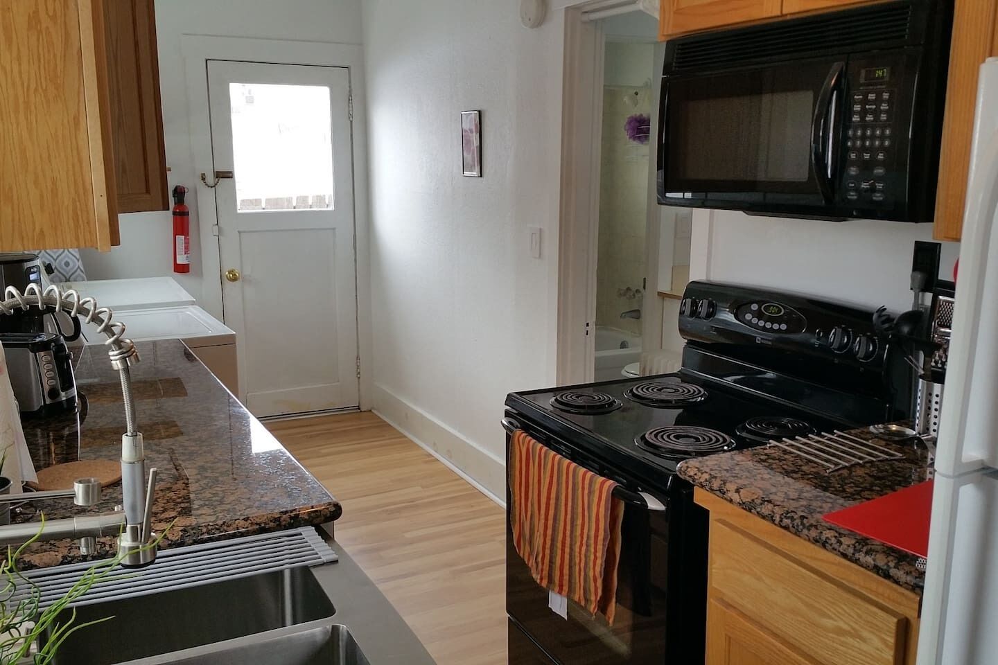 Una cocina compacta con estufa, microondas y pileta.