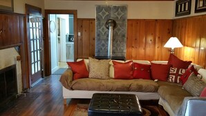 Ein gemütliches Wohnzimmer mit einer Eckcouch, einem Kamin und einer Wandverkleidung.