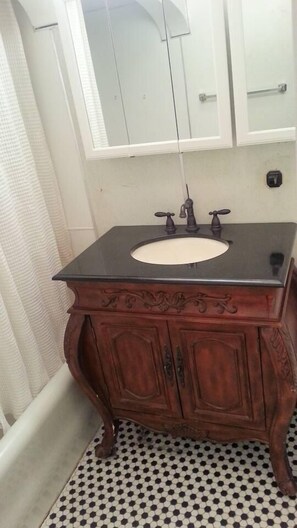 A bathroom with a black sink, wooden vanity, and a mirror above the sink.