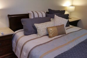 A neatly made bed with multiple pillows and a bedside table with a lamp.