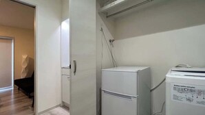 Une cuisine de taille réduite équipée d’un réfrigérateur, d’un lave-linge et d’un petit placard.