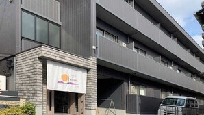 Un immeuble à étages doté d’une architecture moderne, avec une grande banderole bien visible sur laquelle figure un logo et du texte.