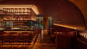 Uma área de bar com balcões de madeira, banquetes e um design de teto curvo.
