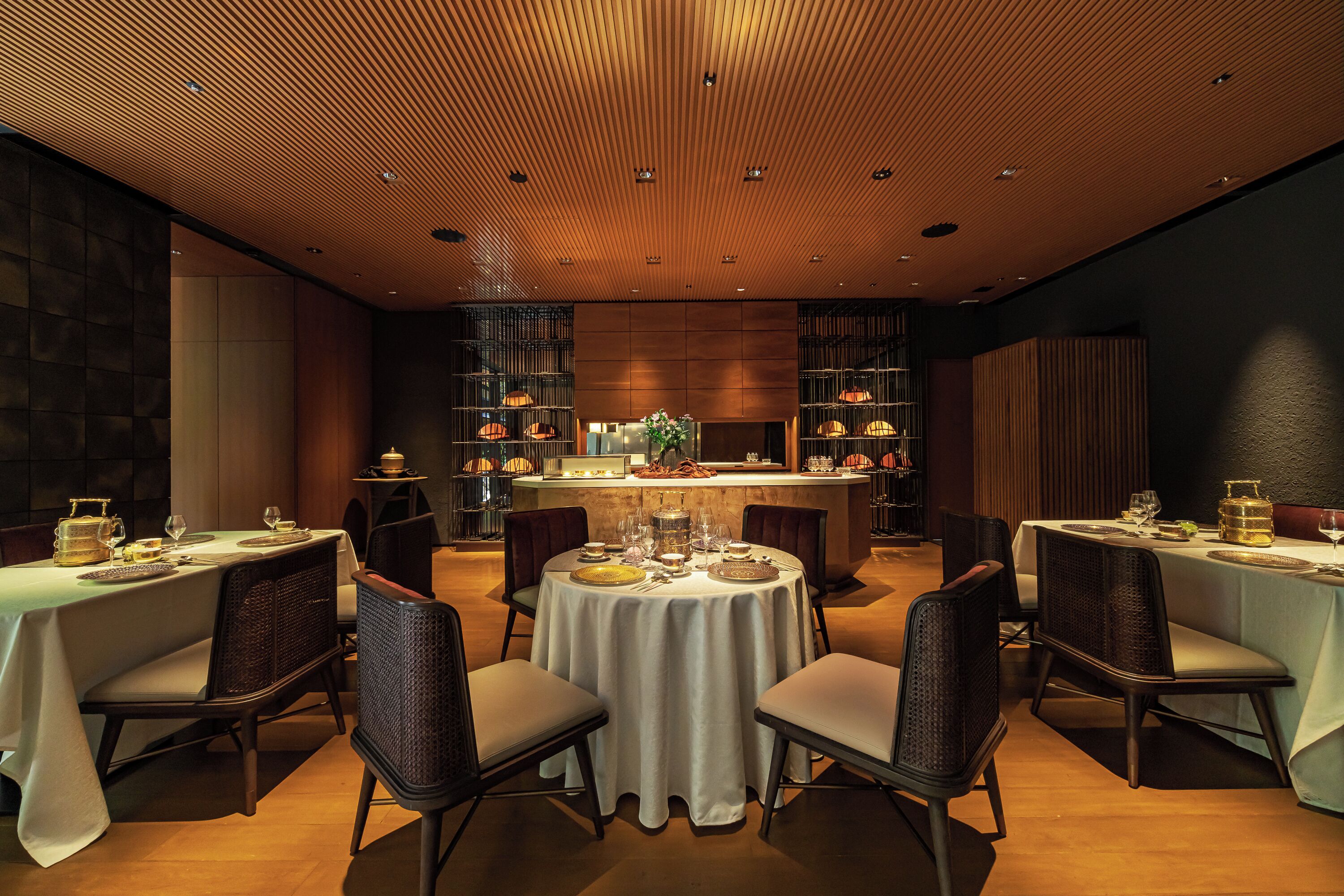 A dining area with round tables, chairs, and a central bar.