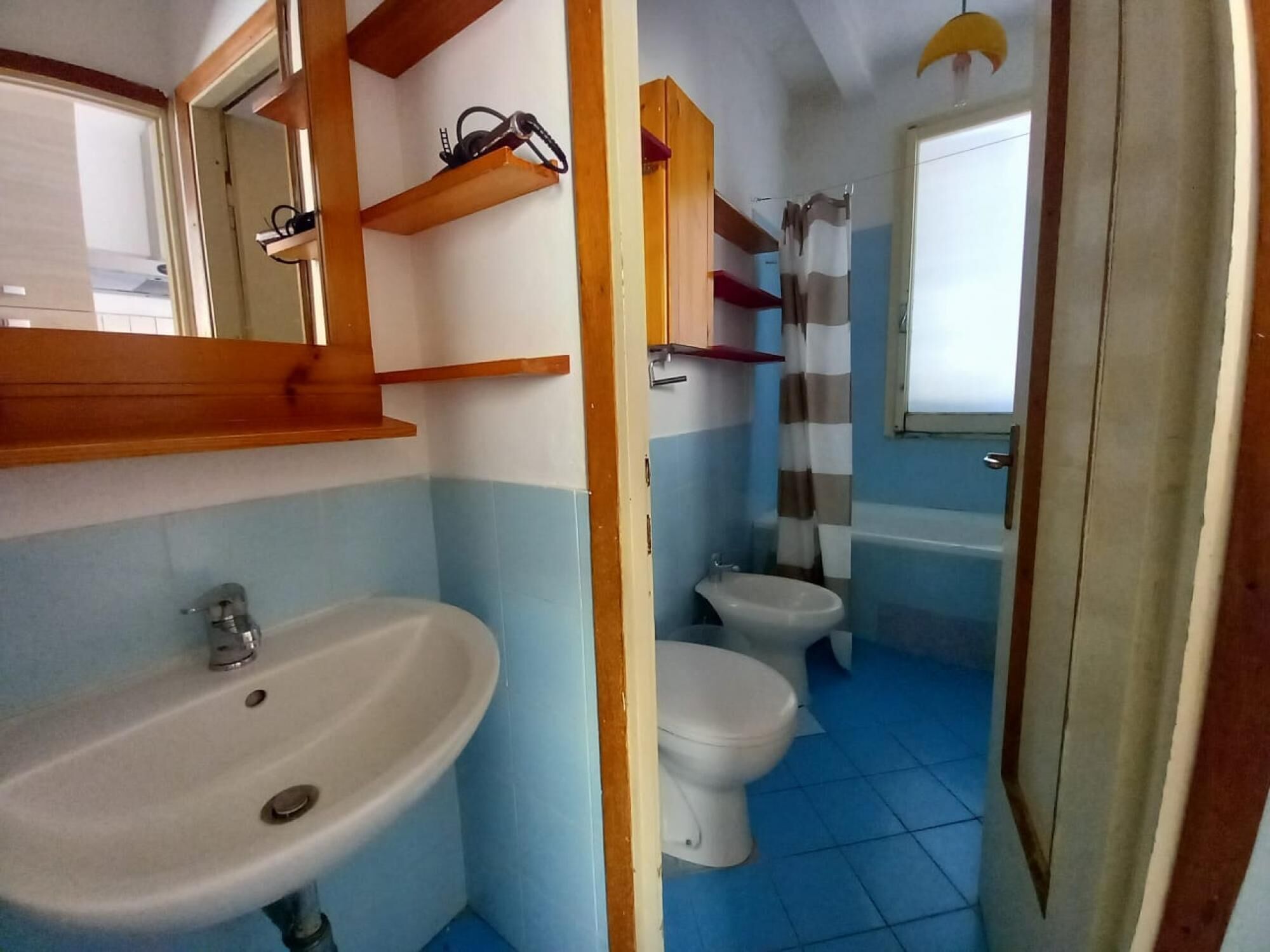 Un baño con lavamanos, dos inodoros, ducha y ventana.