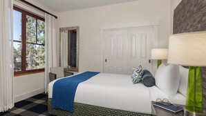 Ein Hotelzimmer mit einem großen Bett, einem Spiegel, einer Tür und einem Fenster mit Vorhängen.