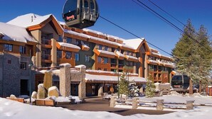 Ein mehrstöckiges Hotel mit Skilift, Steinsäulen und verschneiter Umgebung.