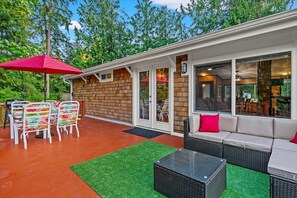 An outdoor patio with a dining table and chairs, a sofa, and a red umbrella.