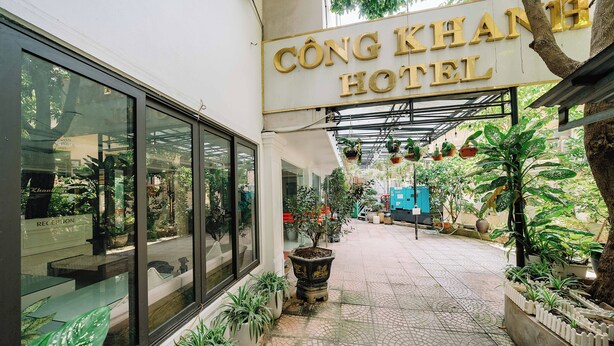 De ingang van het Cộng Khánh Hotel, met een betegeld pad, potplanten en een receptie die zichtbaar is door grote ramen.