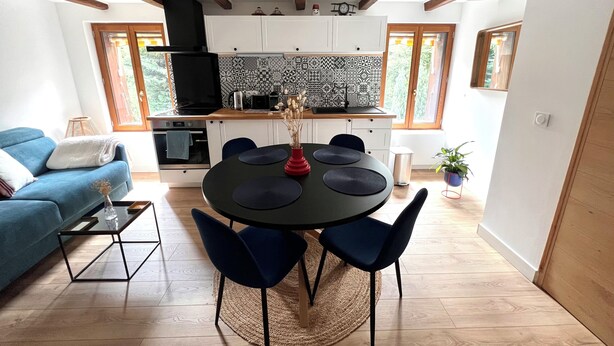 Una cocina moderna con salpicadero estampado, vigas de madera y un comedor con mesa y sillas redondas.