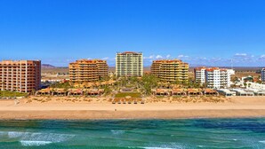 A beachfront hotel with multiple buildings, a sandy beach, and clear blue waters.