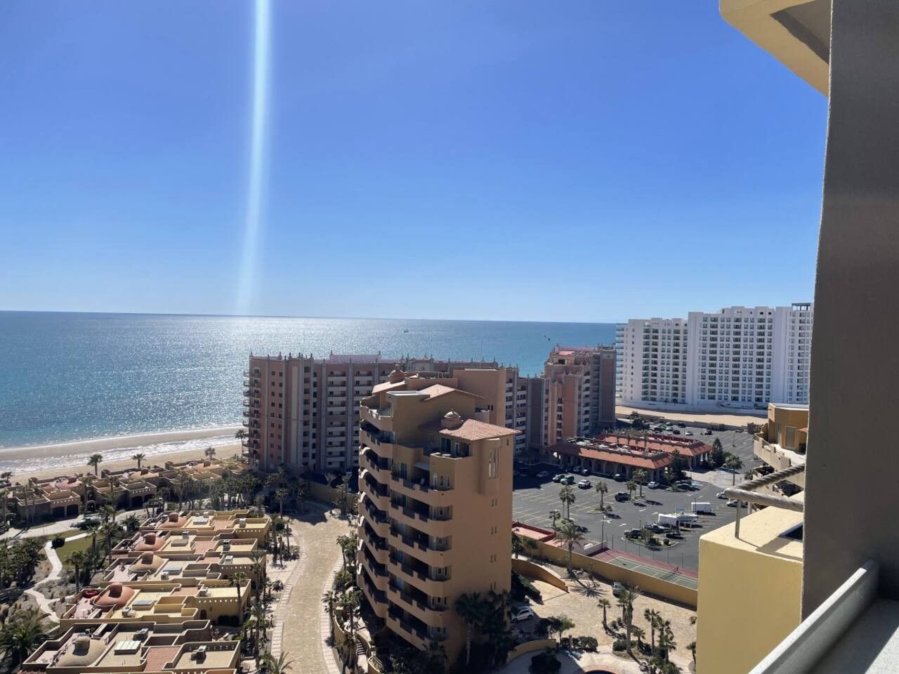 A coastal hotel with multiple buildings, a beach, and a clear sky.