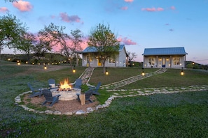 A two-story house with a fire pit and outdoor seating area.