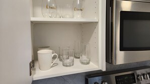 A kitchen with a stainless steel oven and a white shelf holding clear glasses and a white mug. - Family-friendly, clean & affordable 2-BR basement suite close to YEG airport. (Edmonton)