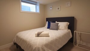 A bedroom with a bed, a window, and a ceiling light. - Family-friendly, clean & affordable 2-BR basement suite close to YEG airport. (Edmonton)