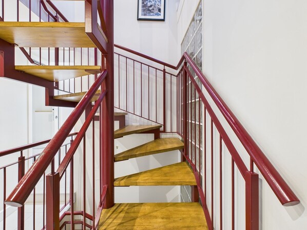 Una escalera con peldaños de madera y barandillas rojas.