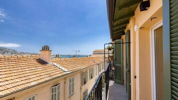 Ein Balkon mit Blick auf Gebäude mit Terrakotta-Dächern und einem strahlend blauen Himmel.