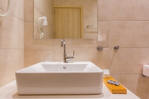 A bathroom with a white sink, a mirror, and a wooden door. - The Perfect Spot Apartments (Rhodes)