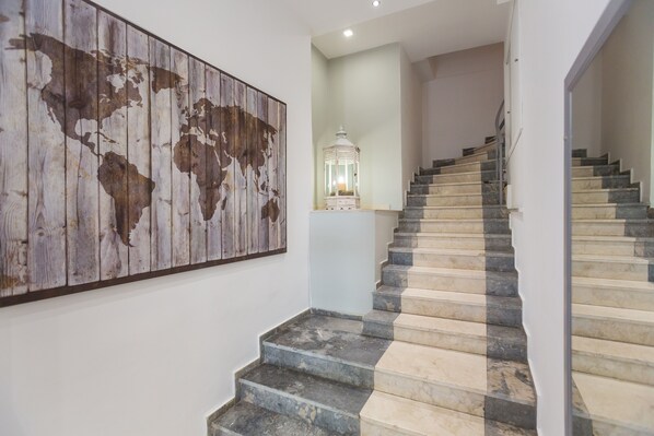 A staircase with alternating dark and light steps, a world map on the wall, and a lantern on the landing. - The Perfect Spot Apartments (Rhodes)