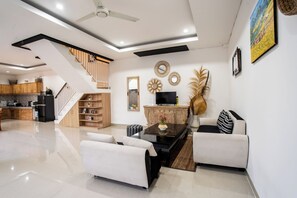 Cozy living area with a seating space, TV, and staircase to an upper level.
