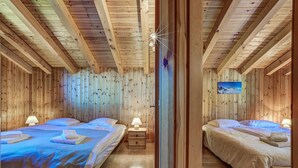 A wooden cabin with two beds, each with a nightstand and lamp.