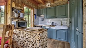 A rustic kitchen with wooden beams, a stone-textured island, and teal cabinetry.
