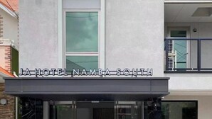 The exterior of JA Hotel Namba South with a modern facade, large glass windows, and a visible balcony.