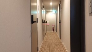 A hotel hallway with doors on both sides, a fire extinguisher, and a sign on the wall.
