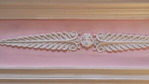 A decorative panel with a symmetrical design featuring a central face and leaf-like patterns. - Large room in historic village center with panoramic view  (Lézat-sur-Lèze)