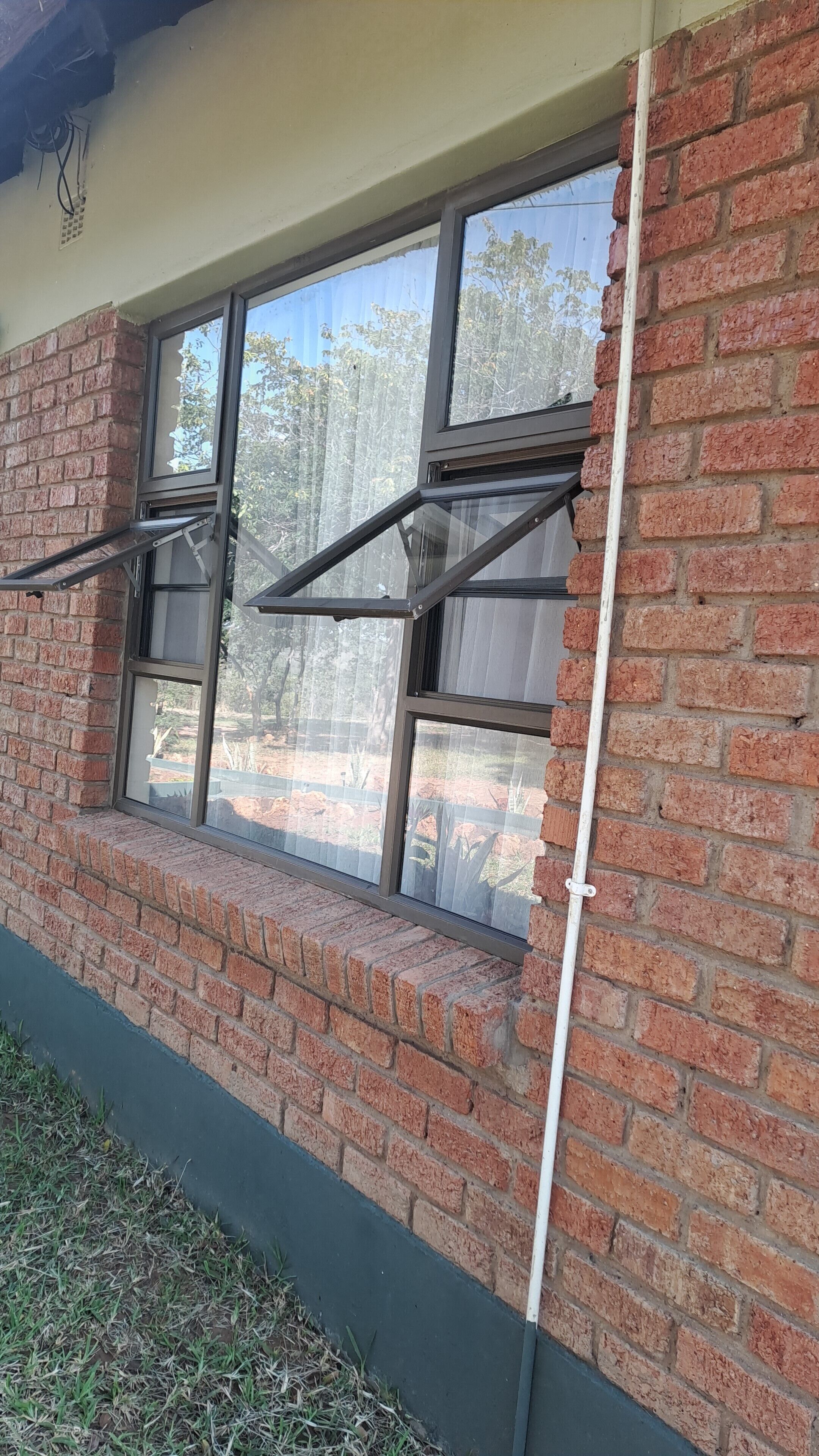 A brick building with a window that has a metal frame and a screen.