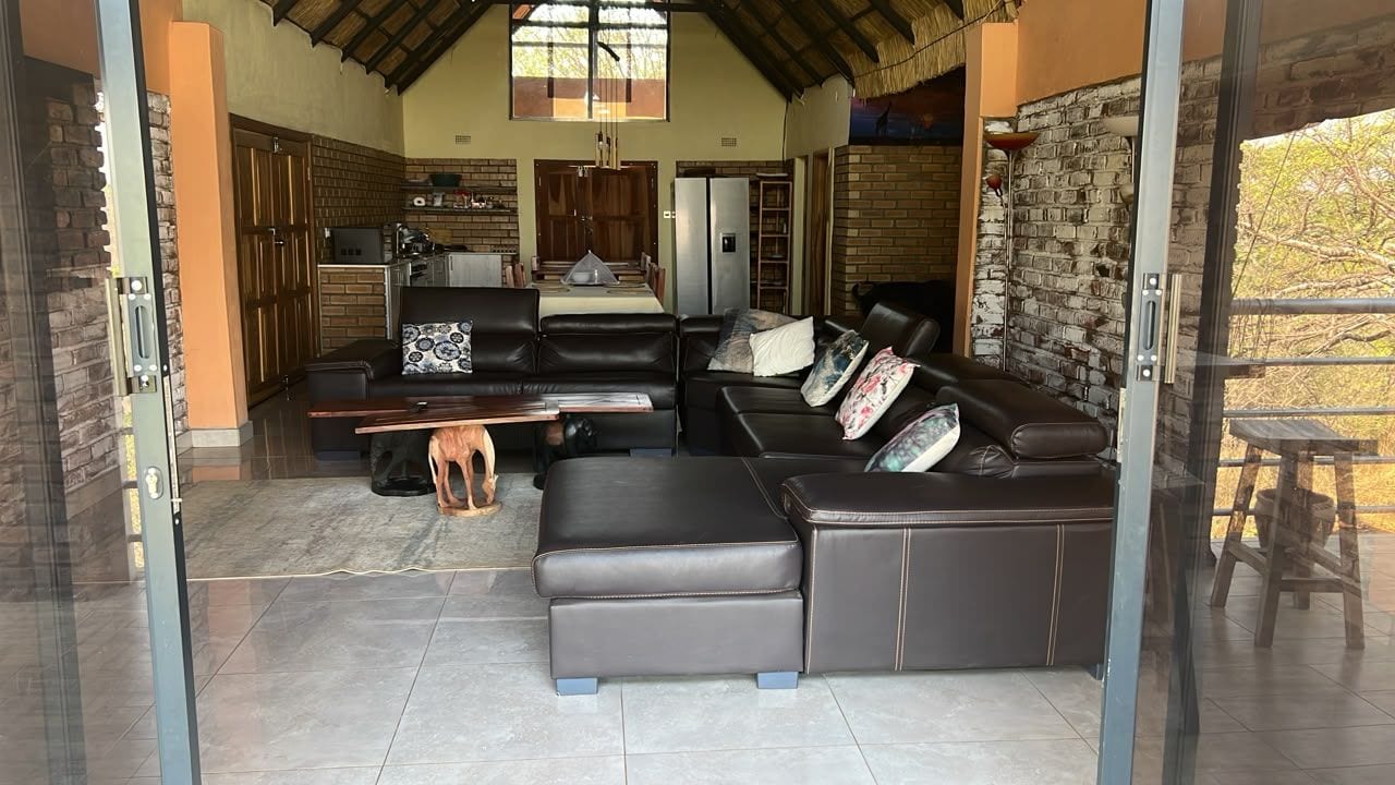 A modern living room with a sectional sofa, a dining area with a table and chairs, and a kitchen in the background.