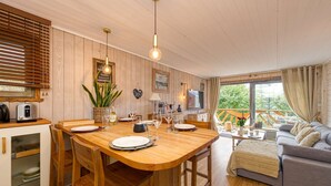 Une pièce chaleureuse avec une table à manger en bois, préparée pour quatre personnes, un canapé et un téléviseur.