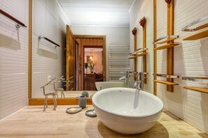 A modern bathroom with a large freestanding bathtub, wooden accents, and a mirror with a wooden frame. - Résidence Hélios - centre station (Alpe d'Huez)