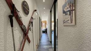 A hallway with skis leaning against the wall, a sign with text, and a framed picture of a mountain scene. - Résidence la Ménandière W1 (Alpe d'Huez)